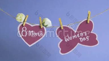 <strong>妇女节</strong>`快乐.. <strong>妇女节</strong>`在粉红色的纸上，挂在一根绳子上，靠近一颗粉红色的心，上面装饰着鲜花。 蓝色